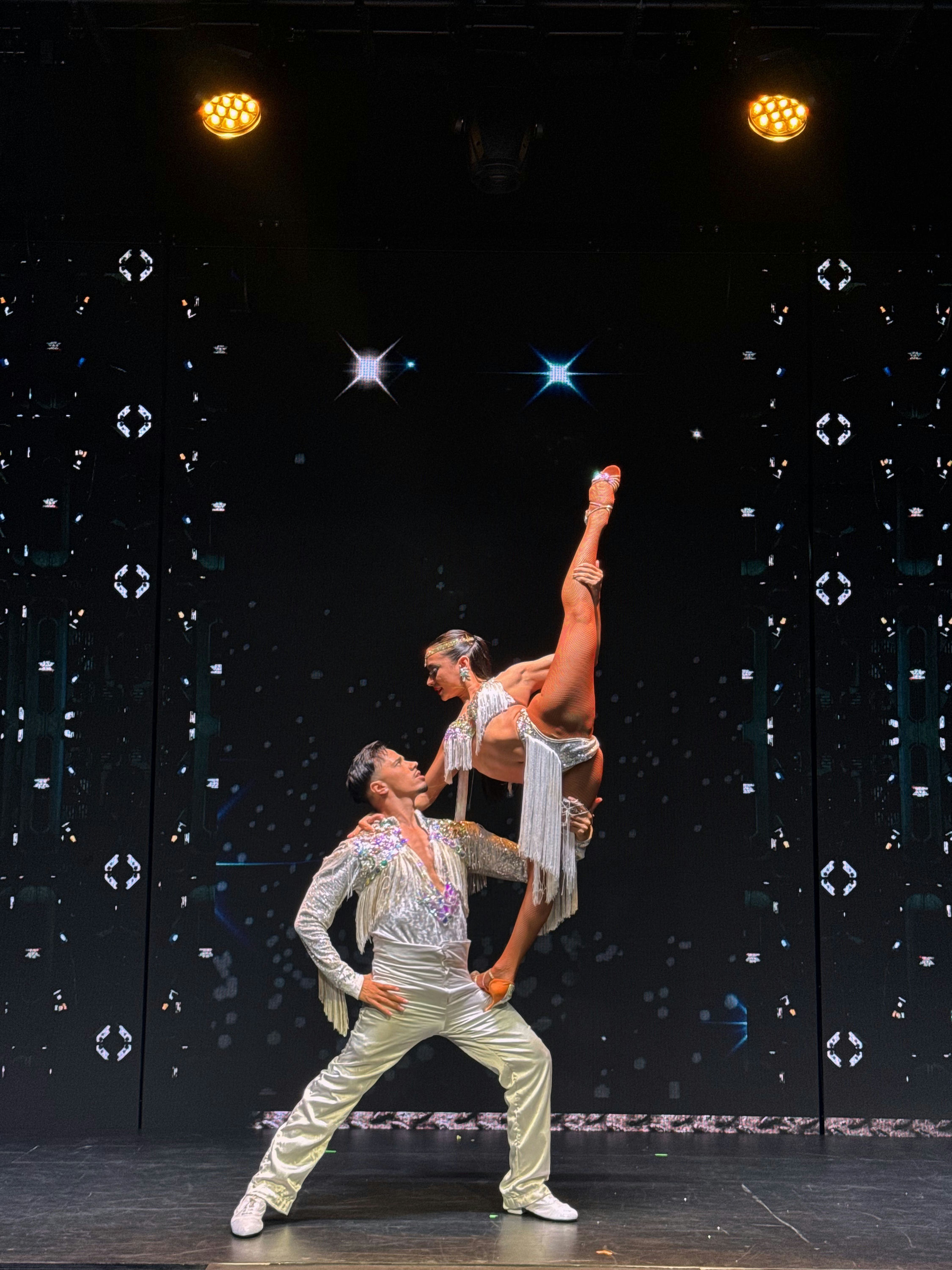 Acrobatic salsa couple performing a lift on stage