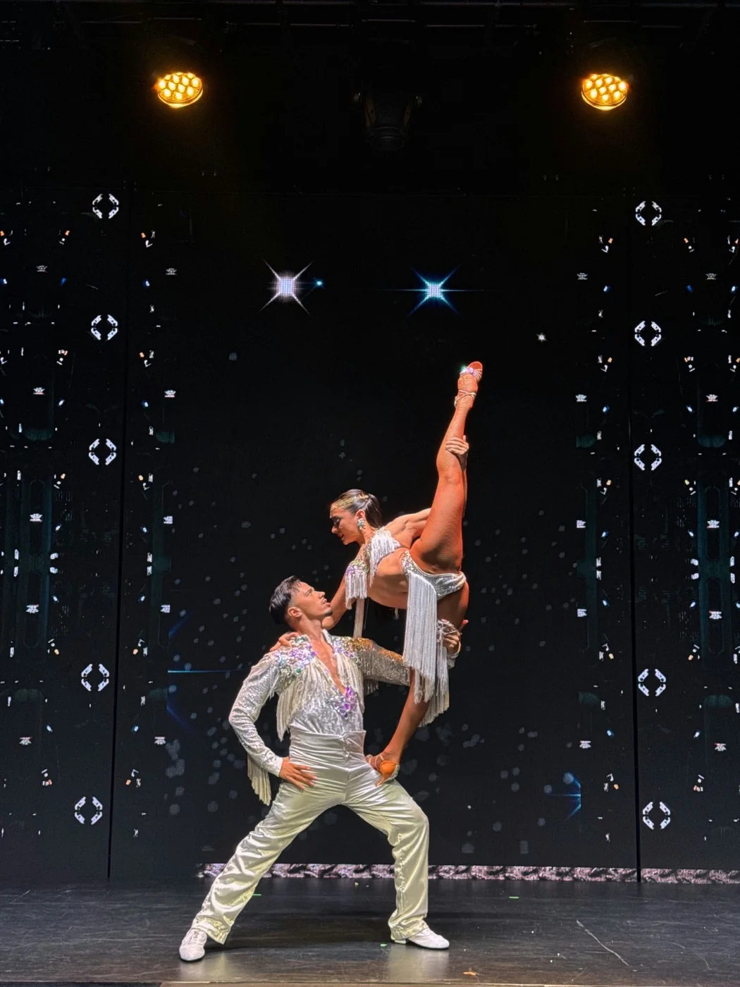 Acrobatic salsa couple performing a lift on stage